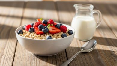 Bowl of plain organic whole grain cereal with fresh berries and milk on wooden table