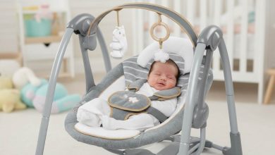 Happy newborn relaxing in plush Ingenuity Swing ‘n Go Deluxe portable baby swing with toy bar